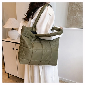 Détail d'un sac cabas en nylon matelassé vert armée porté par un mannequin en intérieur