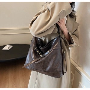 Detail view of deep brown vintage PU leather shoulder bag with textured surface on a model