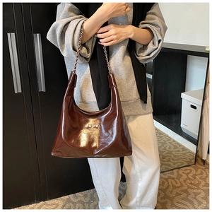 Dettaglio della borsa in vernice marrone con catena argentata e decorazioni a cuore