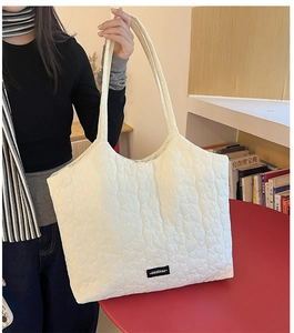 Detail of white tote bag featuring heart quilting pattern and brand label for women