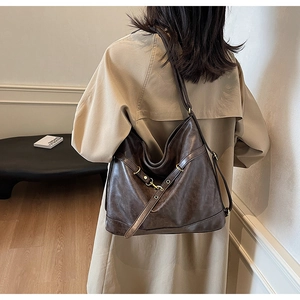 Detail view of large dark brown PU leather hobo bag with vintage buckle straps on a model