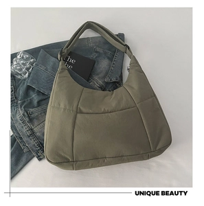 Detail of olive green quilted crossbody bag with wide strap on denim jacket background