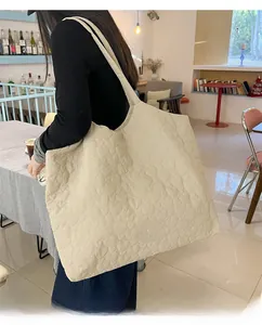 Detail of cream tote bag featuring heart quilted texture and black woven brand label