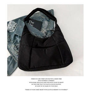 Detail of black quilted puffy bag with square stitching on blue denim jacket background