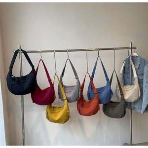 Selection of crescent nylon crossbody bags in eight vibrant colors on a display rack