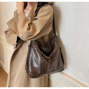 Close-up of a vintage dark brown PU leather hobo bag with bronze buckle detailing