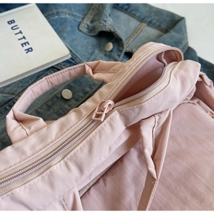 Detailaufnahme der rosa Nylon-Handtasche mit Reißverschluss und plissierter Stoffstruktur