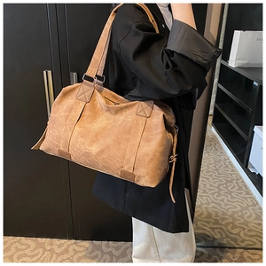Détail d'un sac bandoulière en similicuir marron avec coutures en X et bandoulière large