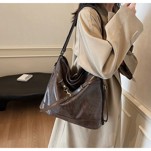 Detailed texture of dark brown faux leather on a casual shoulder bag with golden metal buckle