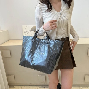 Detail of glossy black mirror finish tote bag with bold white TOTE BAG lettering print