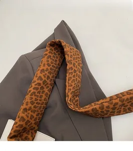 Détail de la bandoulière à imprimé léopard avec coutures fines sur un blazer gris
