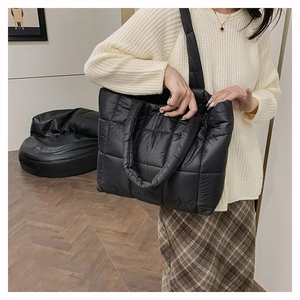 Grand sac cabas noir matelassé en nylon effet doudoune porté par un mannequin en intérieur