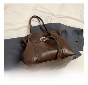 Dettaglio borsa tote marrone scuro con fibbia a C argento e logo del marchio su pelle