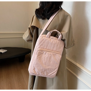 Detail der hellrosa Stoffhandtasche mit Nylonstruktur und Reißverschlusstasche vorne