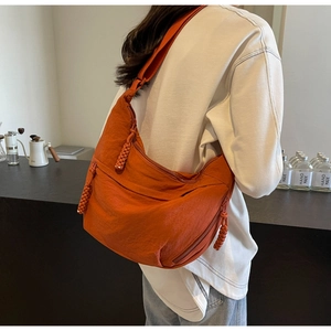 Detail view of large caramel nylon dumpling bag with woven zipper pulls and multiple pockets