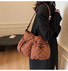 Detail of caramel quilted fabric shoulder bag with drawstrings and padded texture