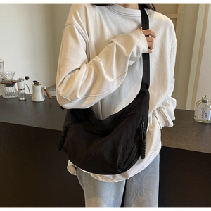 Detail of black crescent crossbody bag showing nylon texture and adjustable strap