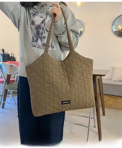 Brown heart-quilted tote bag with textured surface and long shoulder strap detail