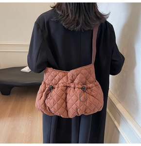 Detail view of quilted warm brown crossbody bag showing drawstring pleats and adjustable buckle