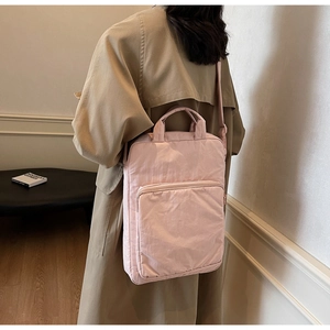 Detail eines hellrosa Nylon-Rucksacks mit verstärktem Griff und verstellbaren Gurten am Modell