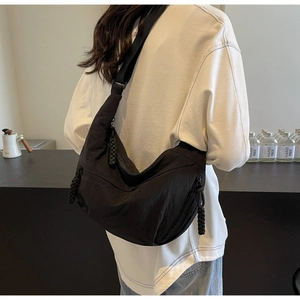 Detailed back view of a black crescent crossbody bag worn in a modern cafe setting
