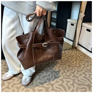 Dettaglio della borsa tote marrone scuro con trama in pelle martellata e fibbia decorativa