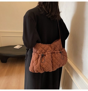 Detail of a brown quilted tote bag with diamond stitching and adjustable drawstring side