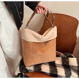 Detail of fuzzy brown suede bucket bag with soft beige shearling trim and leather strap