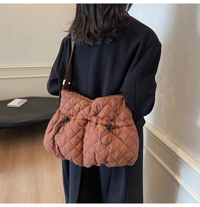 Detail of a brown quilted bubble puffer shoulder bag with nylon drawstring and strap