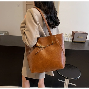 Detail view of brown vintage leather tote bag with side zipper and metal buckle decoration