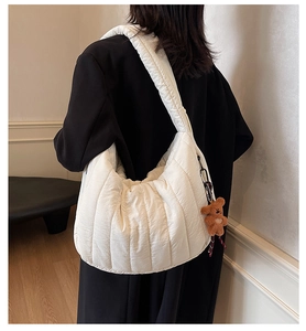 Quilted cloud shoulder bag with brown bear charm shown on model in minimalist interior