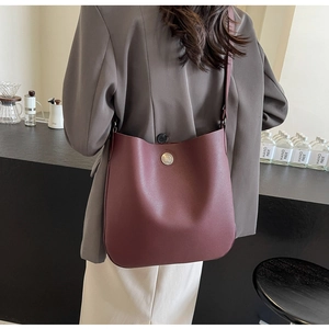 Detail view of burgundy hobo bag in textured faux leather with a silver relief button buckle