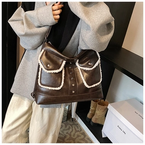 Detail of a dark brown PU leather shoulder bag with fleece trim and metal buttons