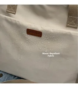 Detail shot showing the water-repellent surface of the beige canvas shoulder bag fabric
