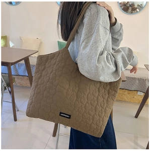 Detail of heart-quilted texture and OUSHANG brand tag on large khaki tote bag