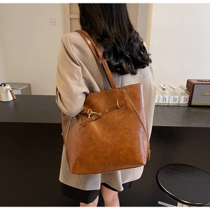 Detail view of large brown vintage tote bag featuring metallic buckle and matte leather texture