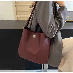 Close-up of wine red bucket bag with lychee texture and vintage metal buckle detail