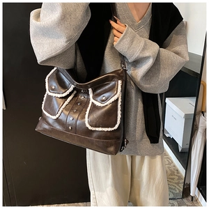 Detail view of dark brown PU leather shoulder bag with white faux shearling trim accents