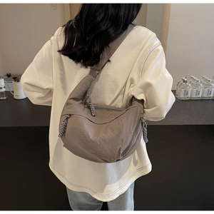 Detail of taupe crescent dumpling bag with woven zipper pull and adjustable strap