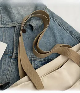 Detailed close-up of cream canvas tote bag showing khaki shoulder strap and zipper closure