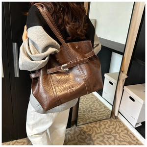 Dettaglio di una grande borsa a tracolla marrone in pelle PU vintage su un modello