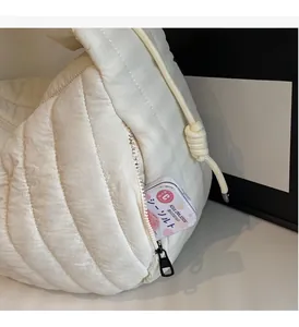 Detail view of a quilted puffer bag side pocket with thick knotted drawstring feature