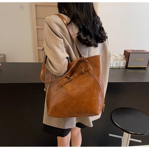 Detail of a vintage brown leather tote bag with buckles and zippers on a model