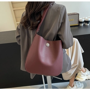 Close-up of a burgundy lychee grain leather tote bag with a round silver metal buckle