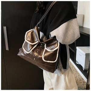 Detail of dark brown leather shoulder bag with white faux fur trim and metal studs