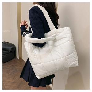Détail d'un grand sac cabas blanc en nylon matelassé porté par un mannequin en intérieur