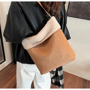 Detail of camel suede tote bag with white sherpa trim shown on shoulder of a model