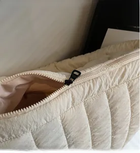 Detail of smooth black zipper closure on a cream quilted fabric crossbody bag