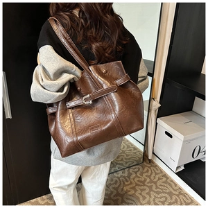 Dettaglio della borsa a spalla in pelle PU marrone vintage con fibbia decorativa e logo