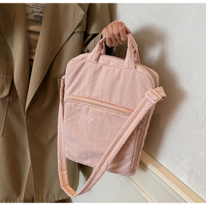 Detail der hellrosa gesteppten Nylon-Umhängetasche mit breitem Gurt und Zipptasche